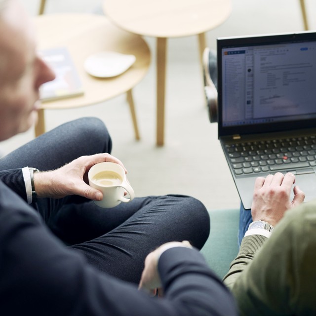 Personen in gesprek met een kop koffie en laptop